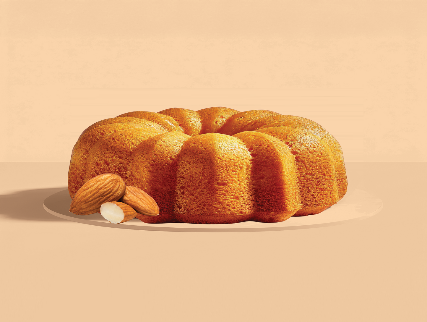 Bundt cake with almonds on a beige background
