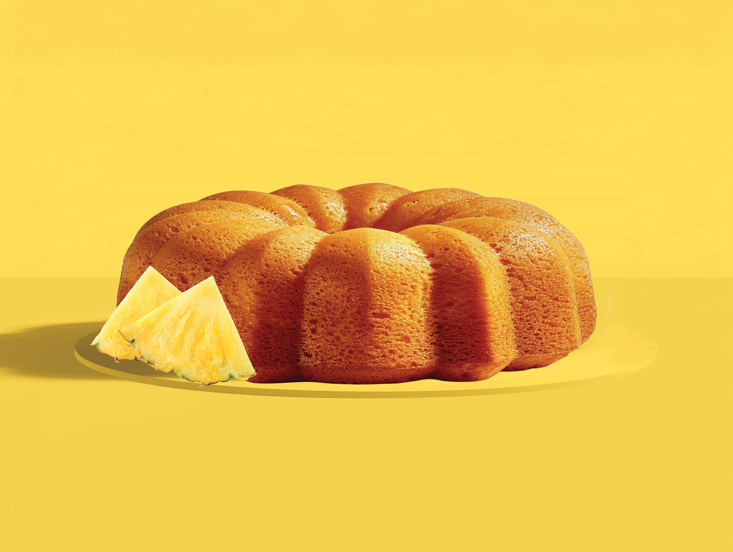 Pineapple Bundt cake with a slice removed on a yellow background
