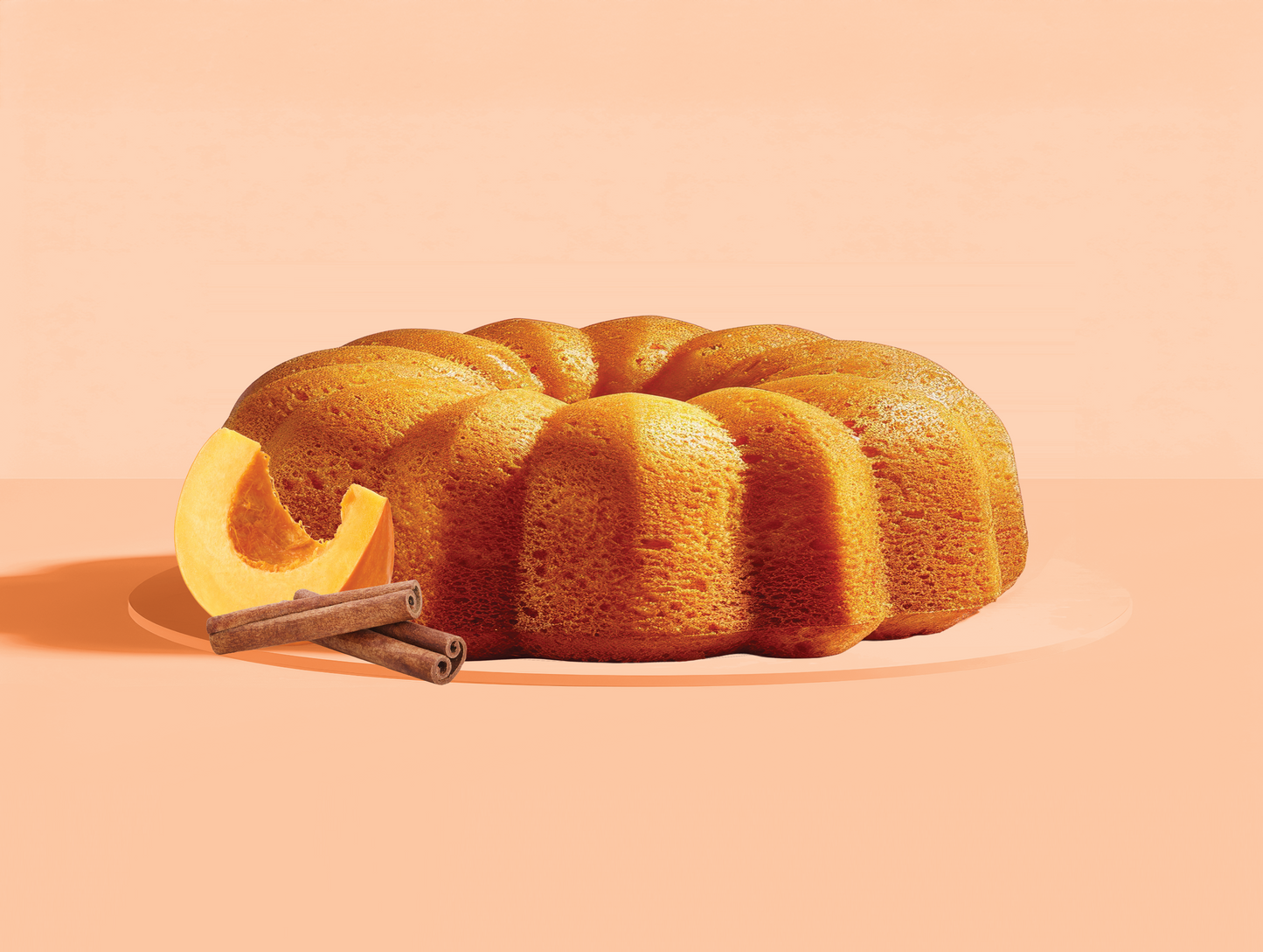 Bundt cake with cinnamon sticks and lemon slices on a peach background