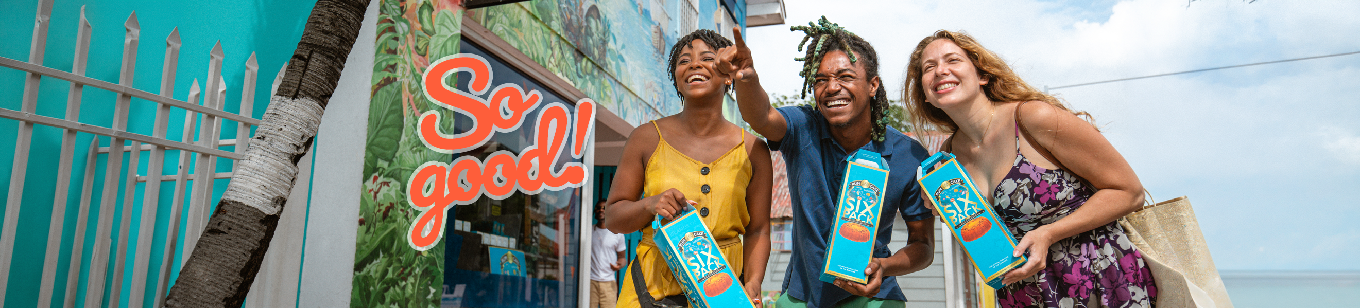 Three people standing outside The Bahamas Rum Cake Factory in downtown Nassau, each holding a six pack of rum cakes. So good!